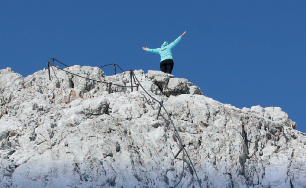 A woman spreading her arms at the top of a mountain
